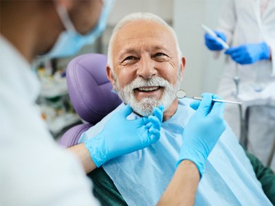 A dentist performing dental work on an older man
