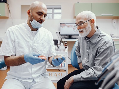 A dentist explaining how to adjust to dentures to a patient